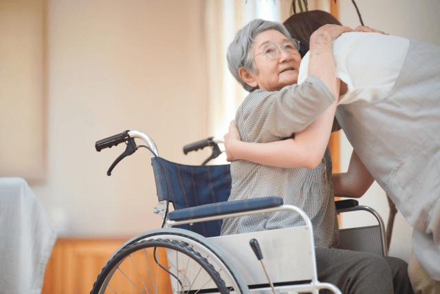 高齢女性を車椅子に乗せる女性介護士