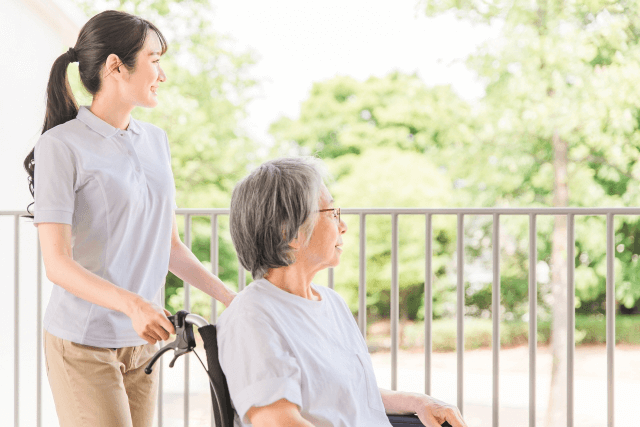 外を見る高齢女性と女性介護士