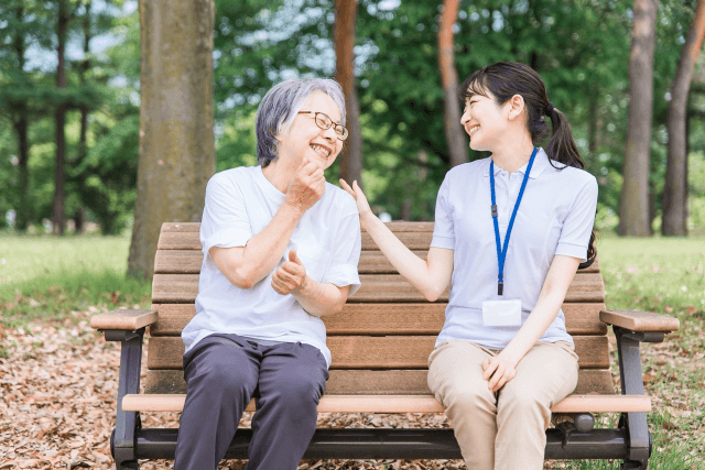 ベンチに座った女性介護士と高齢女性