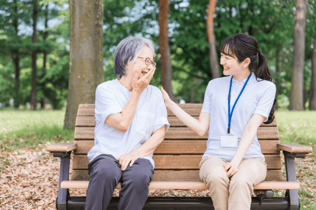 ベンチに座った女性介護士と高齢女性