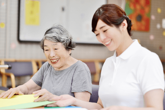 折り紙を折る高齢女性と女性介護士