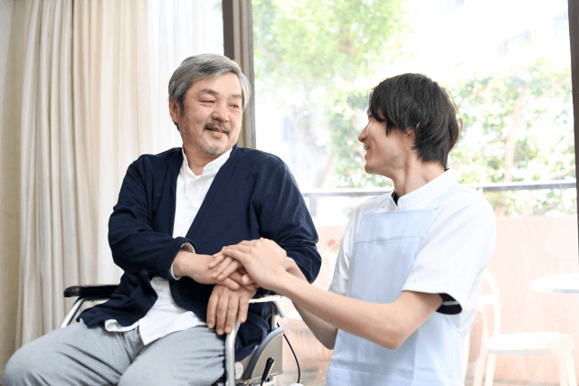 車椅子の高齢男性と男性介護士
