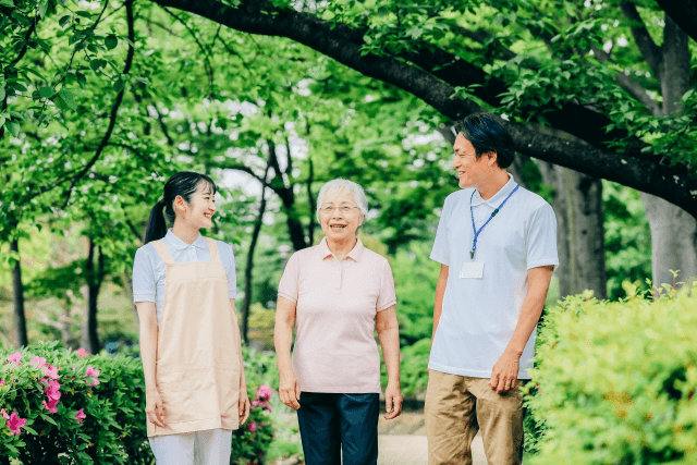 高齢女性と歩く男性介護士と女性介護士