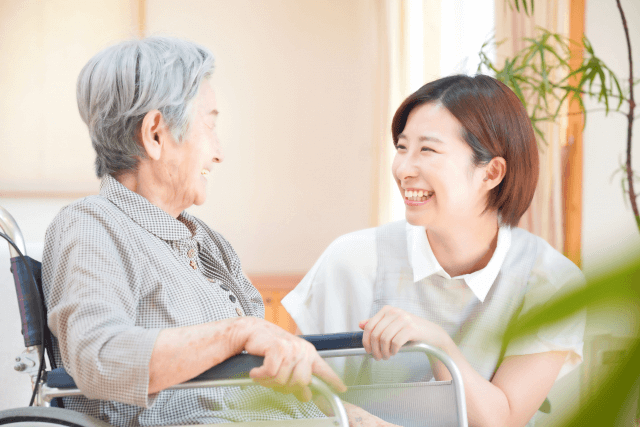 笑顔の女性介護士と車椅子に座っている高齢女性