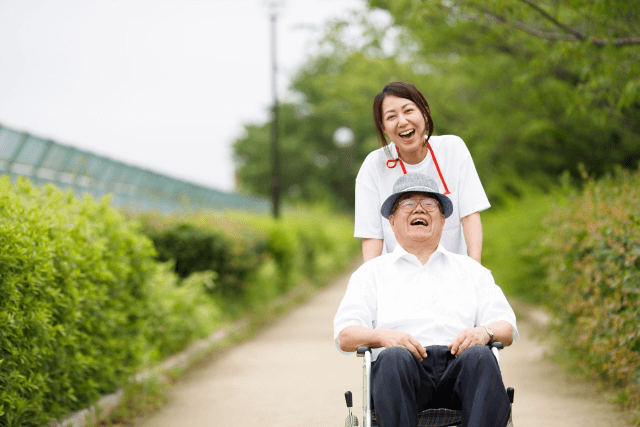 車椅子に座っている高齢男性と車椅子を押す女性介護士