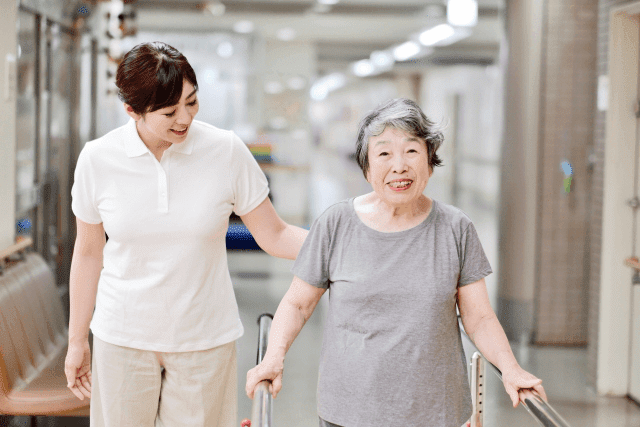 高齢女性の歩行をサポートする女性介護士