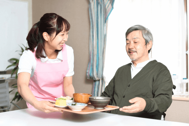 高齢男性に食事を提供する女性介護士