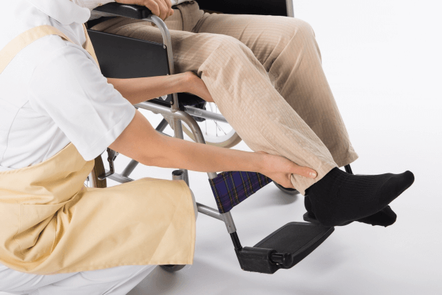 高齢者を車椅子に載せる介護士